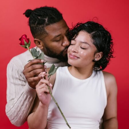 A Black American couple madly in love exchanging a rose and kissing as their preferred Valentine's Day ideas