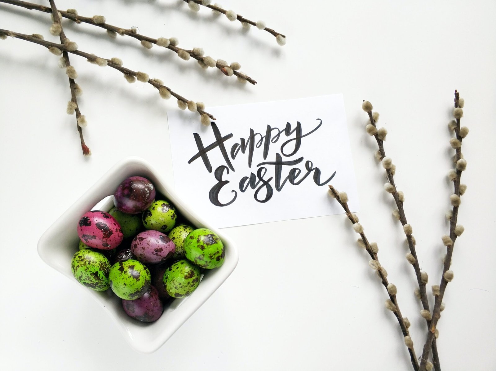 A crate of coloured Easter eggs surrounded by a bouquet of flowers and "Happy Easter" sign.