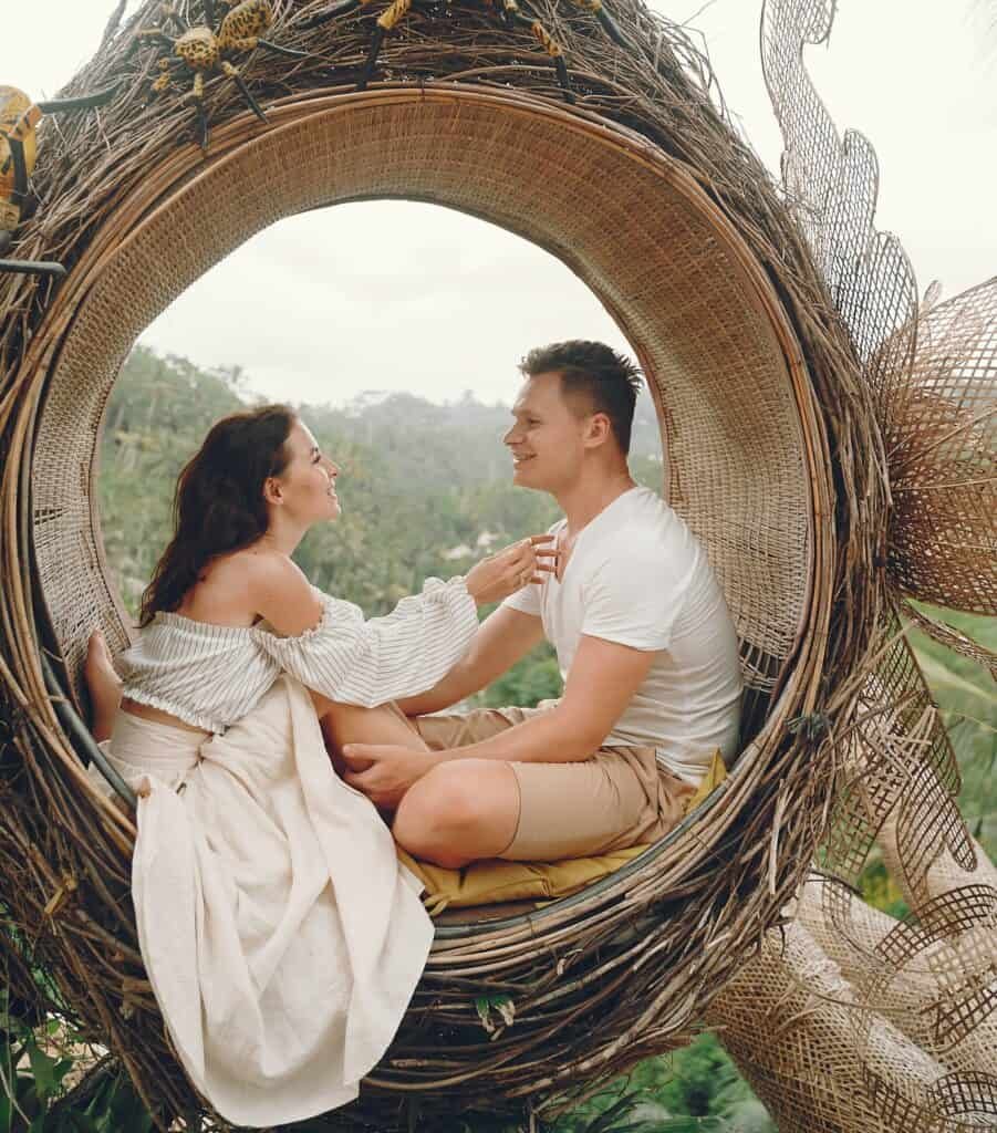 A happy couple relaxing in a circular swing seat during the honeymoon stage in marriage
