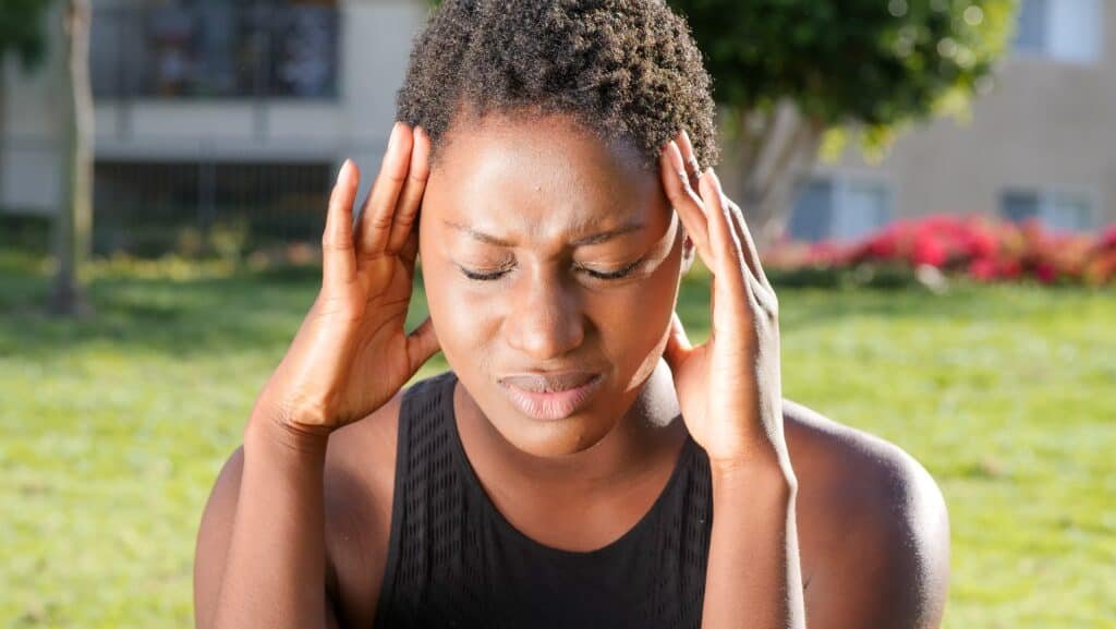 Surprising causes of headaches: when to seek urgent help? 1 A Black lady holding her head and with her eyes closed in obvious pain from migraine headaches