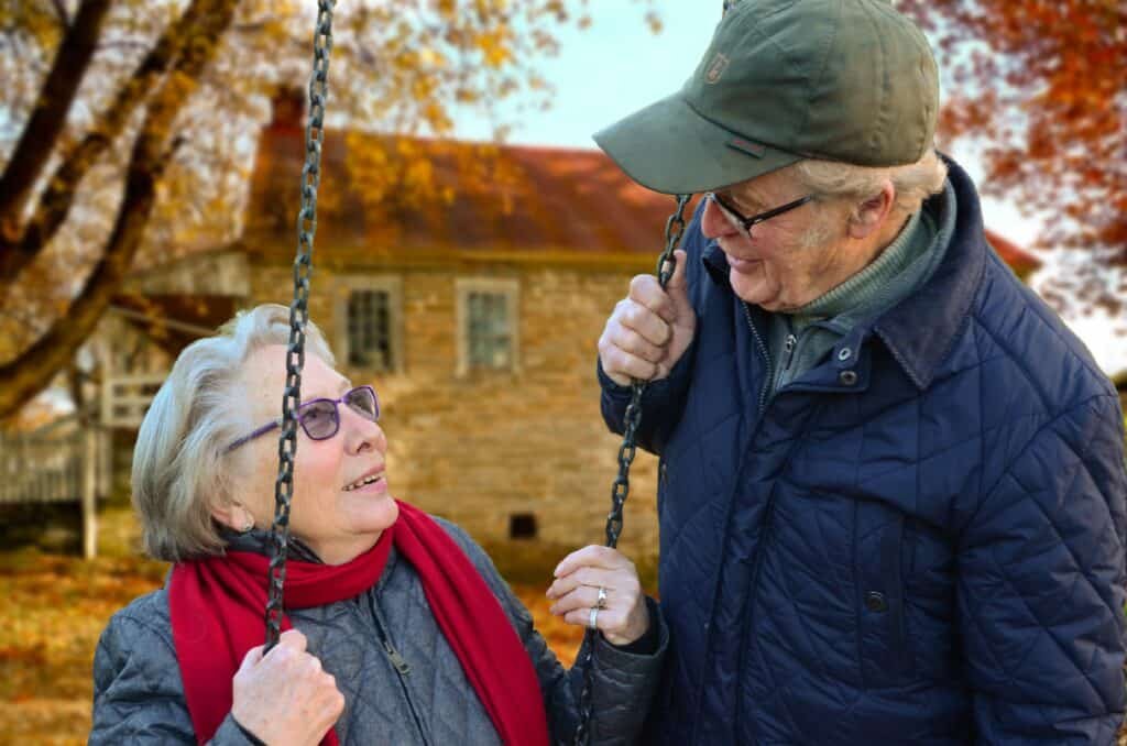 A happy elderly couple enjoying a happy moment with the husband pushing his wife on a swing. 