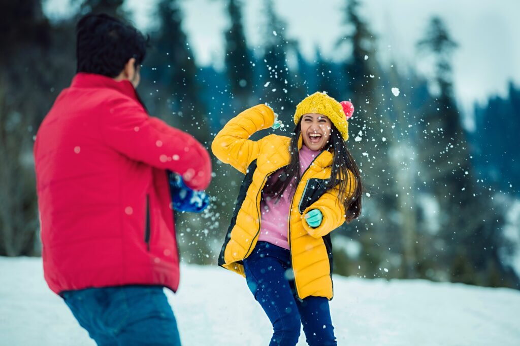 A couple wearing Winter clothes are involved in snow play as expression of a healthy work-life balance