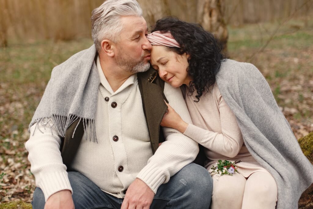 Research reveals the Secrets to long-lasting and happy marriages 2 A middle aged couple cuddling and kissing while seating in the woods.
