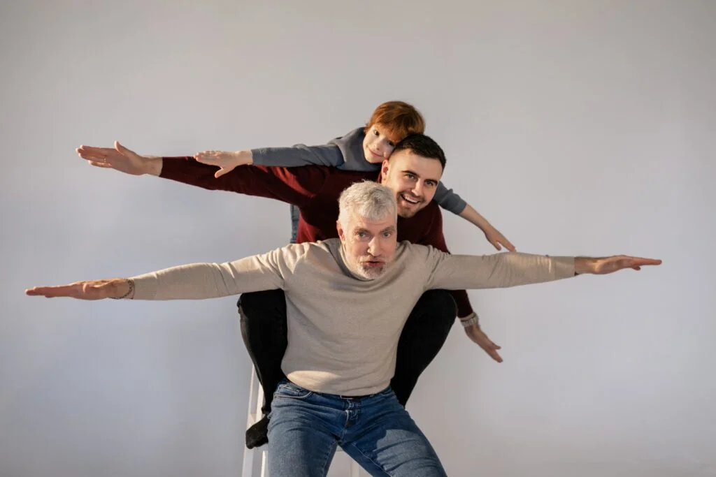 A man is a flying pose with his son and grandson, demonstrating qualities of a good father