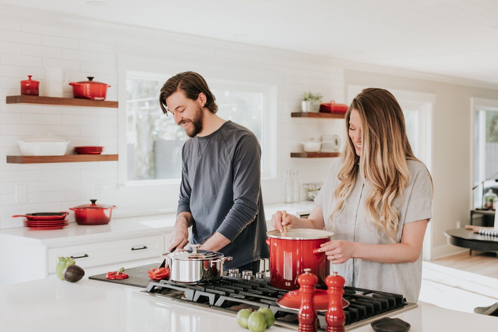 A young couple who are cooking together in their kitchen smiling about their friendship in marriage