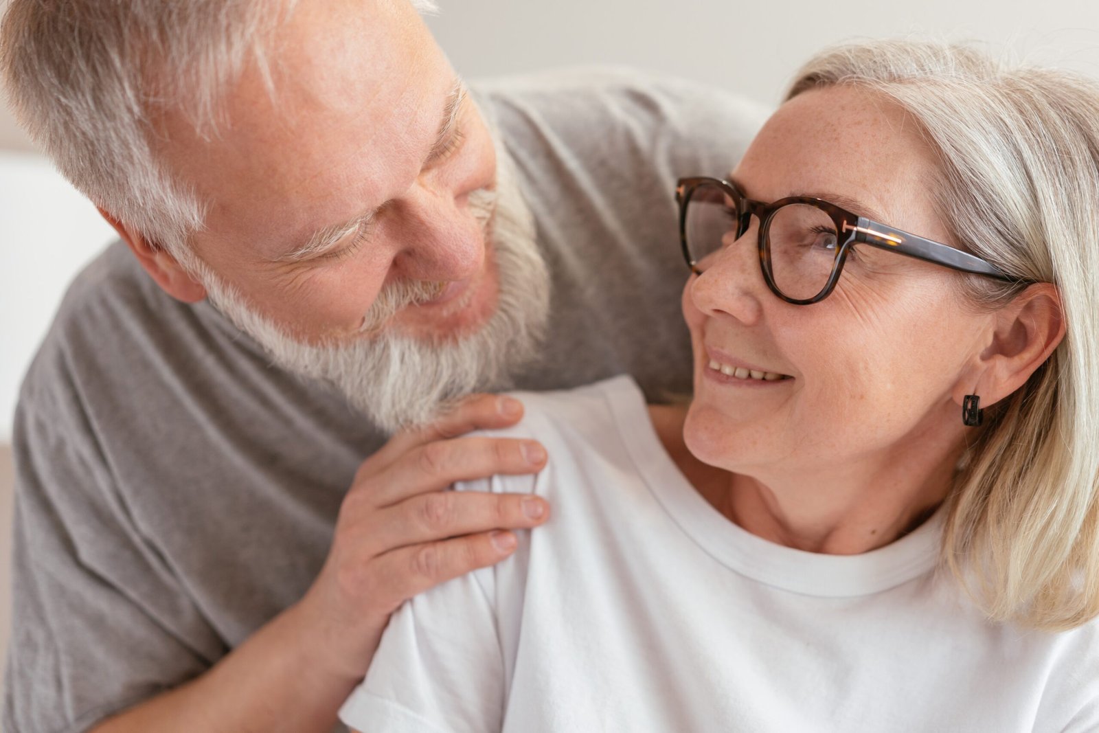 An elderly couple who are smiling and gazing into each other's eyes, content with earning their trust in marriage