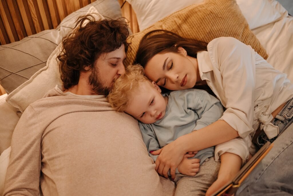 Navigating the Transition to Parenthood as a New Parent 2 An exhausted couple deep asleep while cuddling their partly awake baby as they struggle to transition to parenthood