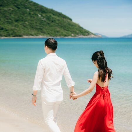 A young couple holding hands walking by the beach during their honeymoon stage of relationship.