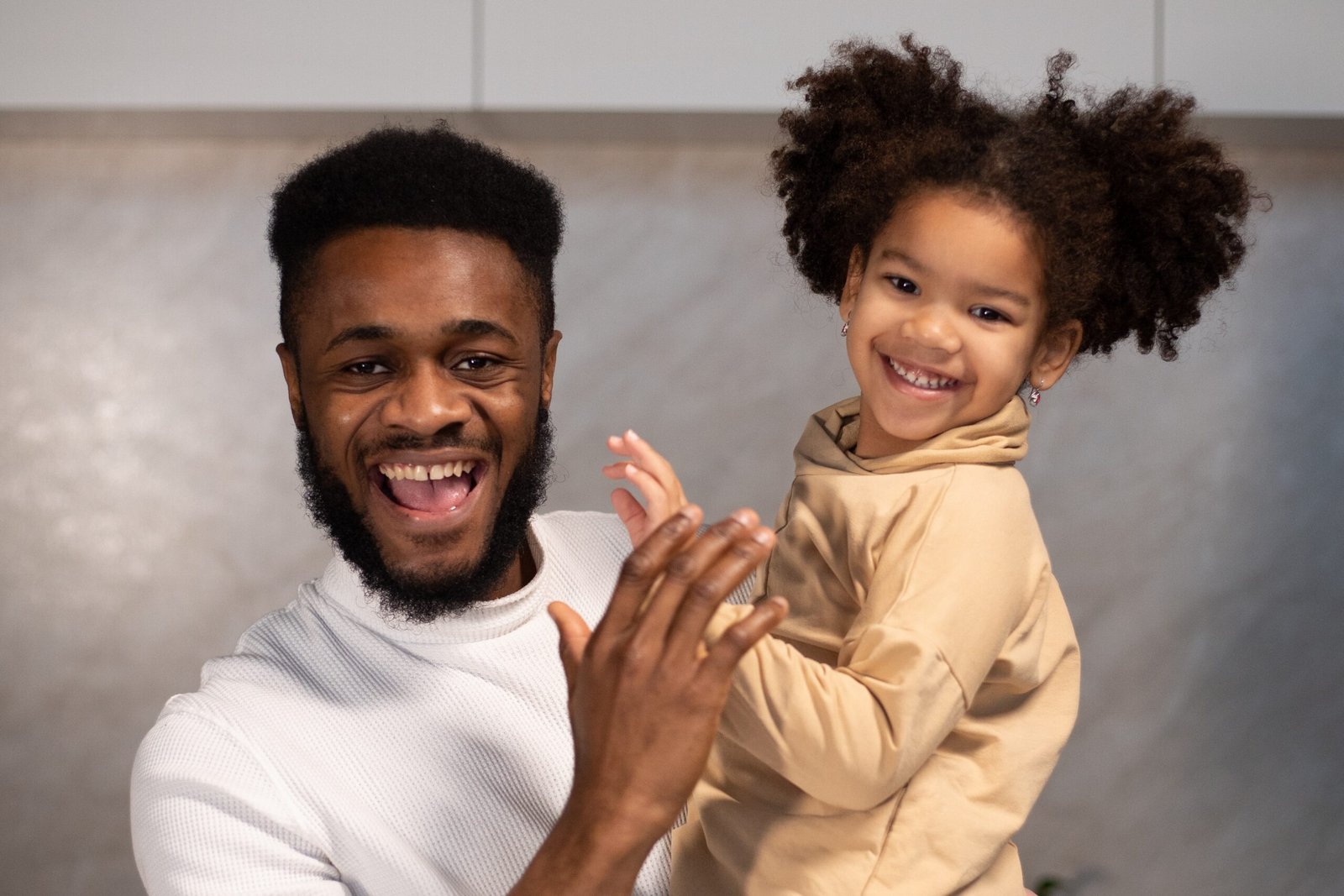 A happy African dad and his pretty daughter looking straight to the camera, the former content of being a good father.