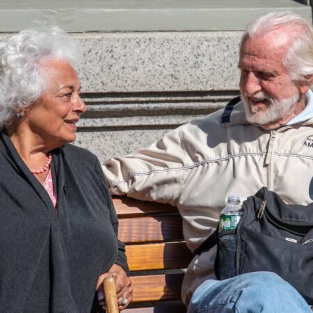 Elderly Black couple seated at a bench in long-term relationships