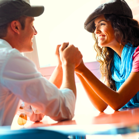 A young couple are holding hands and smiling while telling each other uplifting words of affirmation at the end of a great day.