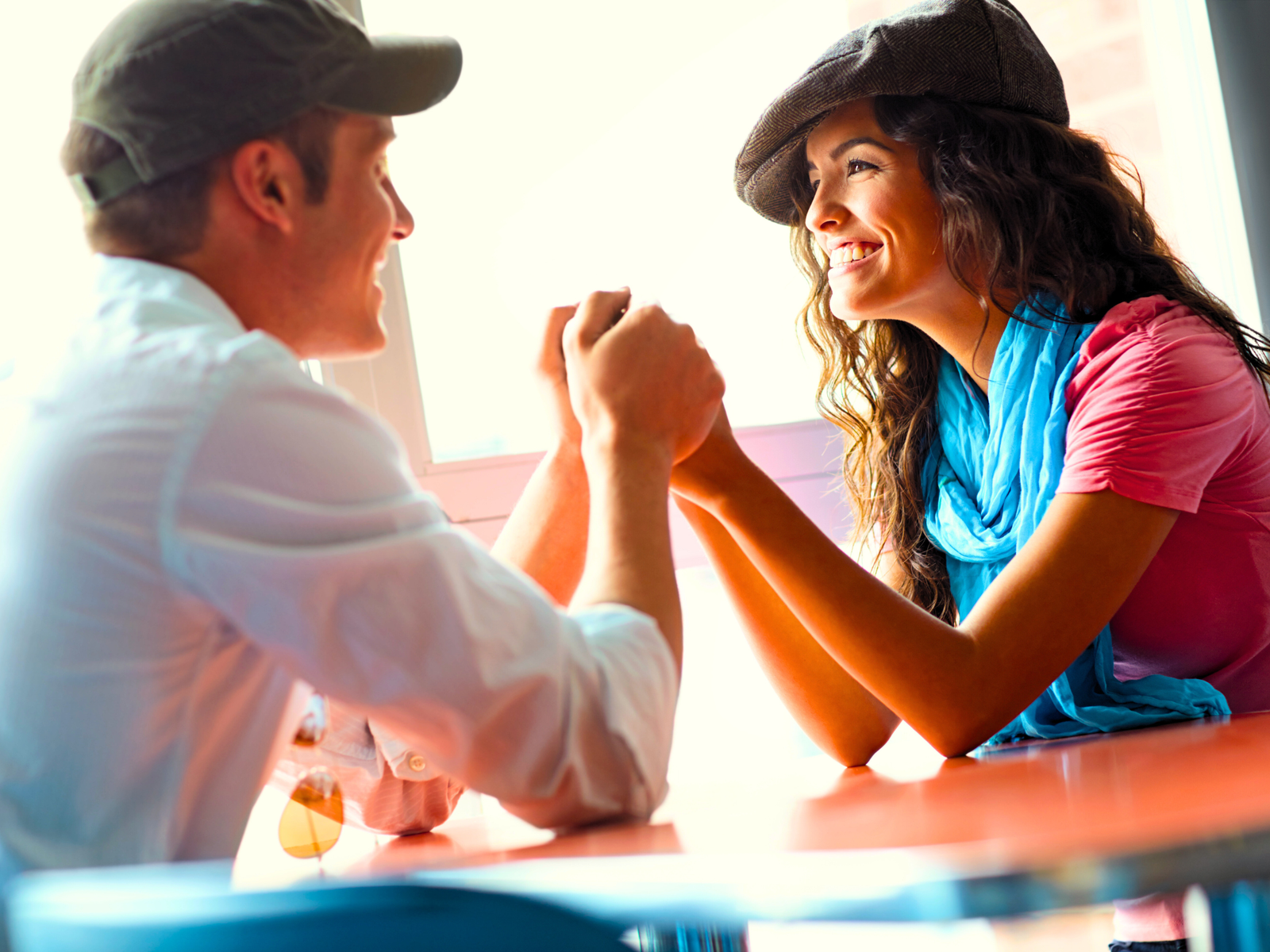A young couple are holding hands and smiling while telling each other uplifting words of affirmation at the end of a great day.
