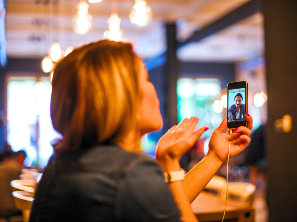 A lady is blowing kisses to her fiancé while on a video call to him,