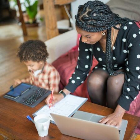 A photo showing a mum working from home while guiding her son in honoring motherhood.